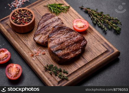 Delicious fresh juicy beef steak with spices and herbs on a dark concrete background. Grilled dish