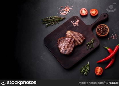 Delicious fresh juicy beef steak with spices and herbs on a dark concrete background. Grilled dish