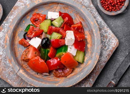 Delicious fresh juicy greek salad with feta cheese, olives, peppers, tomatoes, cucumber and onions on a gray concrete background