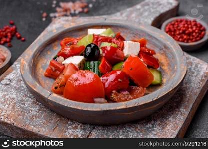 Delicious fresh juicy greek salad with feta cheese, olives, peppers, tomatoes, cucumber and onions on a gray concrete background