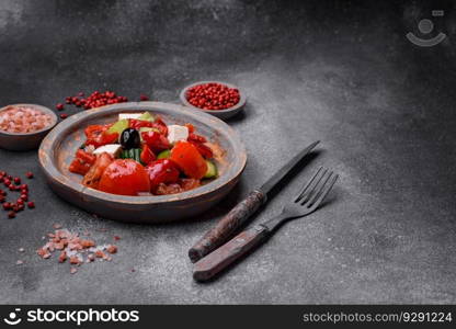 Delicious fresh juicy greek salad with feta cheese, olives, peppers, tomatoes, cucumber and onions on a gray concrete background