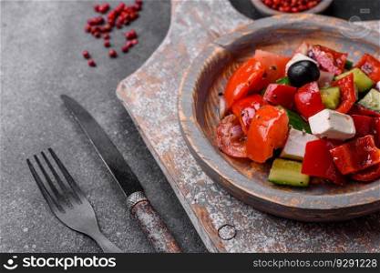 Delicious fresh juicy greek salad with feta cheese, olives, peppers, tomatoes, cucumber and onions on a gray concrete background