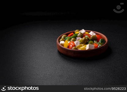 Delicious fresh, juicy Greek salad with feta cheese, olives, tomatoes, cucumber, pepper, salt and spices on a dark concrete background