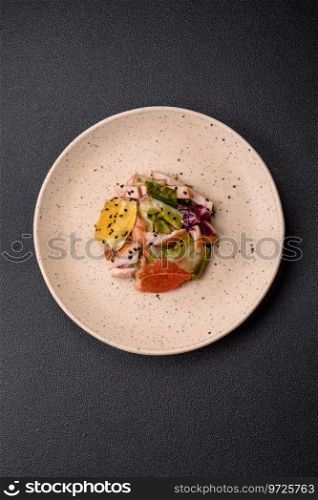 Delicious fresh juicy salad of sliced chicken, grapefruit, lettuce, sesame with olive oil on a ceramic plate on a concrete background