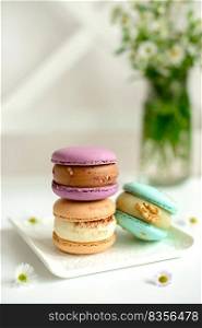 Delicious fresh macaroons with filling on a light wooden background. Sweet dessert for coffee. Delicious fresh macaroons with filling on a light wooden background