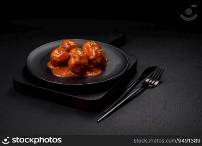 Delicious fresh meatballs in tomato sauce with salt, spices and herbs on a dark concrete background