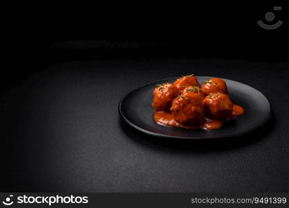 Delicious fresh meatballs in tomato sauce with salt, spices and herbs on a dark concrete background