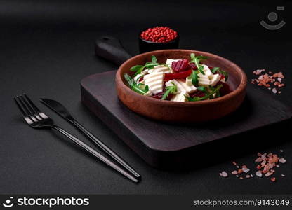 Delicious fresh mozzarella and boiled beets cut into slices on a round ceramic plate on a dark concrete background