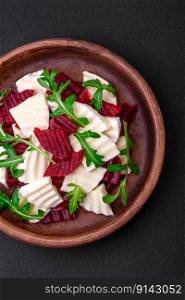Delicious fresh mozzarella and boiled beets cut into slices on a round ceramic plate on a dark concrete background