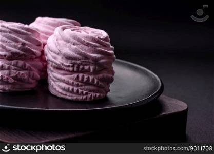 Delicious fresh natural airy marshmallows on a black ceramic plate on a dark concrete background