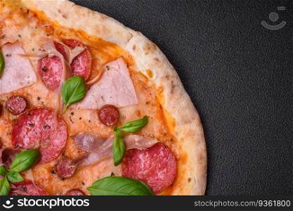 Delicious fresh oven baked pizza with salami, meat, cheese, tomatoes, spices and herbs on a dark concrete background. Delicious fresh oven baked pizza with salami, meat, cheese, tomatoes