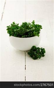 delicious fresh parsley inside a white bowl on wooden table