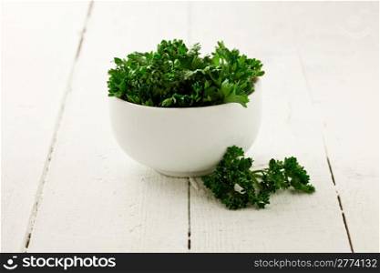 delicious fresh parsley inside a white bowl on wooden table
