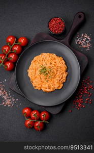 Delicious fresh pasta consisting of thin noodles, red pesto rosso sauce with salt, spices and herbs on a dark concrete background