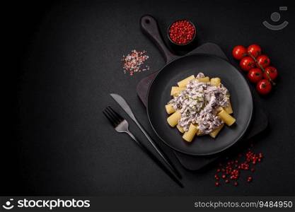 Delicious fresh pasta with ch&ignon mushrooms in a creamy sauce with salt, spices and herbs on a dark concrete background