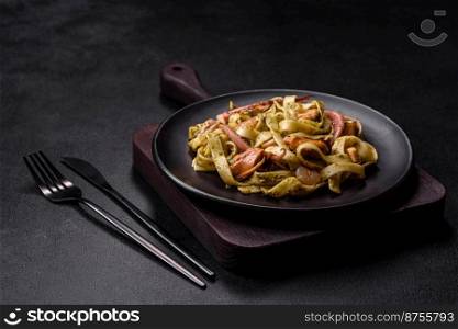 Delicious fresh pasta with pesto sauce and seafood on a black plate against a dark concrete background. Delicious fresh pasta with pesto sauce and seafood on a black plate