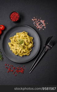 Delicious fresh pasta with pesto sauce, salt, spices and herbs on a ceramic plate on a textured concrete background