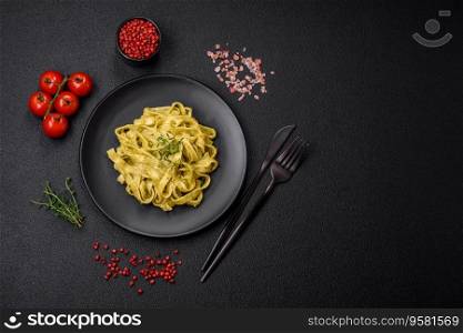 Delicious fresh pasta with pesto sauce, salt, spices and herbs on a ceramic plate on a textured concrete background