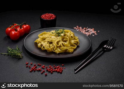 Delicious fresh pasta with pesto sauce, salt, spices and herbs on a ceramic plate on a textured concrete background