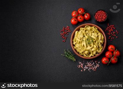 Delicious fresh pasta with pesto sauce, salt, spices and herbs on a ceramic plate on a textured concrete background