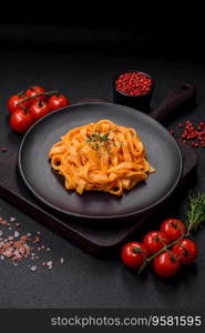  Delicious fresh pasta with pesto sauce, salt, spices and herbs on a ceramic plate on a textured concrete background