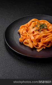  Delicious fresh pasta with pesto sauce, salt, spices and herbs on a ceramic plate on a textured concrete background