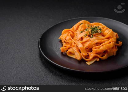  Delicious fresh pasta with pesto sauce, salt, spices and herbs on a ceramic plate on a textured concrete background