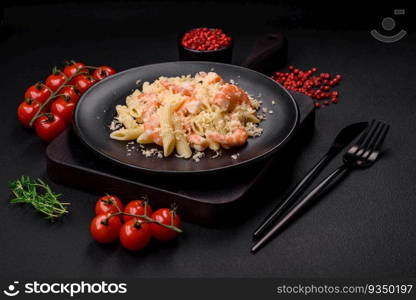 Delicious fresh penna pasta with shrimp, sauce, cheese, salt and spices on a dark concrete background. Delicious fresh penna pasta with shrimp, sauce, cheese, salt and spices