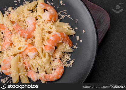 Delicious fresh penna pasta with shrimp, sauce, cheese, salt and spices on a dark concrete background. Delicious fresh penna pasta with shrimp, sauce, cheese, salt and spices