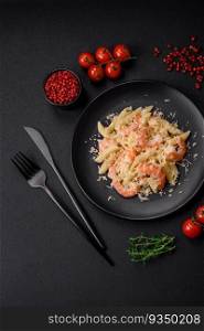 Delicious fresh penna pasta with shrimp, sauce, cheese, salt and spices on a dark concrete background. Delicious fresh penna pasta with shrimp, sauce, cheese, salt and spices
