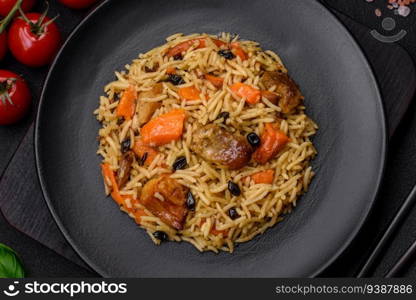 Delicious fresh pilaf with rice, carrots, meat, onions, spices and berries on a ceramic plate on a dark concrete background