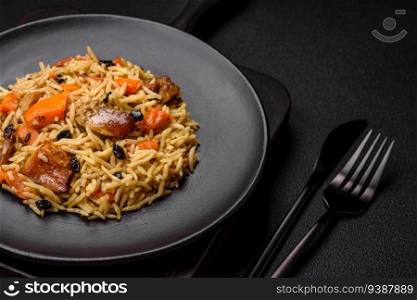 Delicious fresh pilaf with rice, carrots, meat, onions, spices and berries on a ceramic plate on a dark concrete background