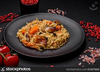 Delicious fresh pilaf with rice, carrots, meat, onions, spices and berries on a ceramic plate on a dark concrete background
