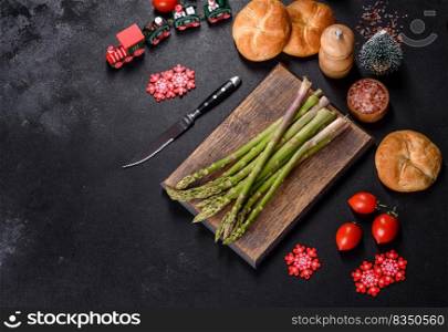 Delicious fresh raw green asparagus stalks on wooden cutting board on festive Christmas table. Delicious fresh raw green asparagus stalks on wooden cutting board