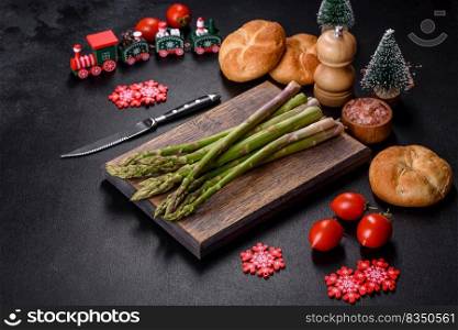 Delicious fresh raw green asparagus stalks on wooden cutting board on festive Christmas table. Delicious fresh raw green asparagus stalks on wooden cutting board