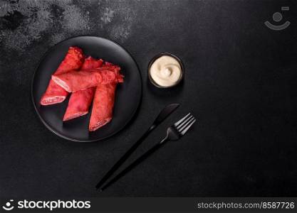 Delicious fresh red pancakes topped with beetroot juice with cheese and eggs on a dark concrete background. Delicious fresh red pancakes topped with beetroot juice with cheese and eggs