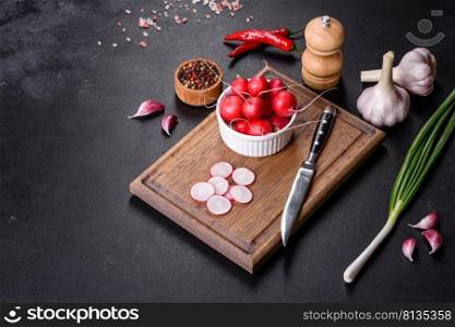 Delicious fresh red radish as ingredient to make spring salad on wooden cutting board against dark concrete background. Delicious fresh red radish as ingredient to make spring salad on wooden cutting board