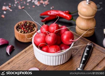 Delicious fresh red radish as ingredient to make spring salad on wooden cutting board against dark concrete background. Delicious fresh red radish as ingredient to make spring salad on wooden cutting board