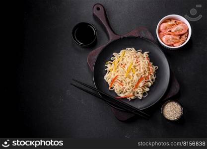 Delicious fresh rice noodles with shrimp, spices and herbs on a dark concrete background. Delicious fresh rice noodles with shrimp, spices and herbs