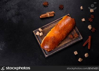 Delicious fresh roll with apricot jam on a dark concrete background. Delicious homemade pastries. Delicious fresh roll with apricot jam on a dark concrete background