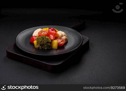 Delicious fresh salad of broccoli, cauliflower, sweet peppers and cherry tomatoes with spices and salt on a dark concrete background