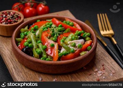 Delicious fresh salad of green beans, peas, sweet peppers and cheese with salt and spices on a dark concrete background