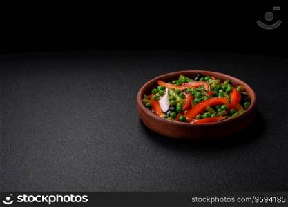 Delicious fresh salad of green beans, peas, sweet peppers and cheese with salt and spices on a dark concrete background