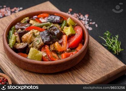Delicious fresh salad of grilled vegetables peppers, tomatoes, eggplants and zucchini with salt and spices on a dark concrete background