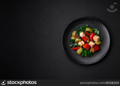 Delicious fresh salad of zucχni, cheese, sweet peppers, sπnach with sπces and herbs in a ceramic plate on a dark concrete background