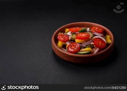 Delicious fresh salad with beef slices, cherry tomatoes, sweet peppers, salt, spices and herbs on a textured concrete background