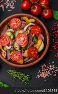 Delicious fresh salad with beef slices, cherry tomatoes, sweet peppers, salt, spices and herbs on a textured concrete background