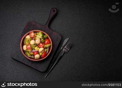 Delicious fresh salad with broccoli, cherry tomatoes, mushrooms, onions, salt, spices and herbs on a dark concrete background