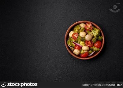 Delicious fresh salad with broccoli, cherry tomatoes, mushrooms, onions, salt, spices and herbs on a dark concrete background