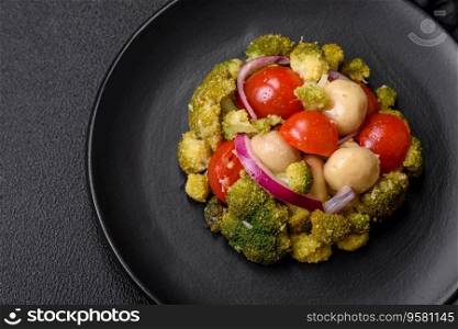 Delicious fresh salad with broccoli, cherry tomatoes,μshrooms, onions, sa<, sπces and herbs on a dark concrete background